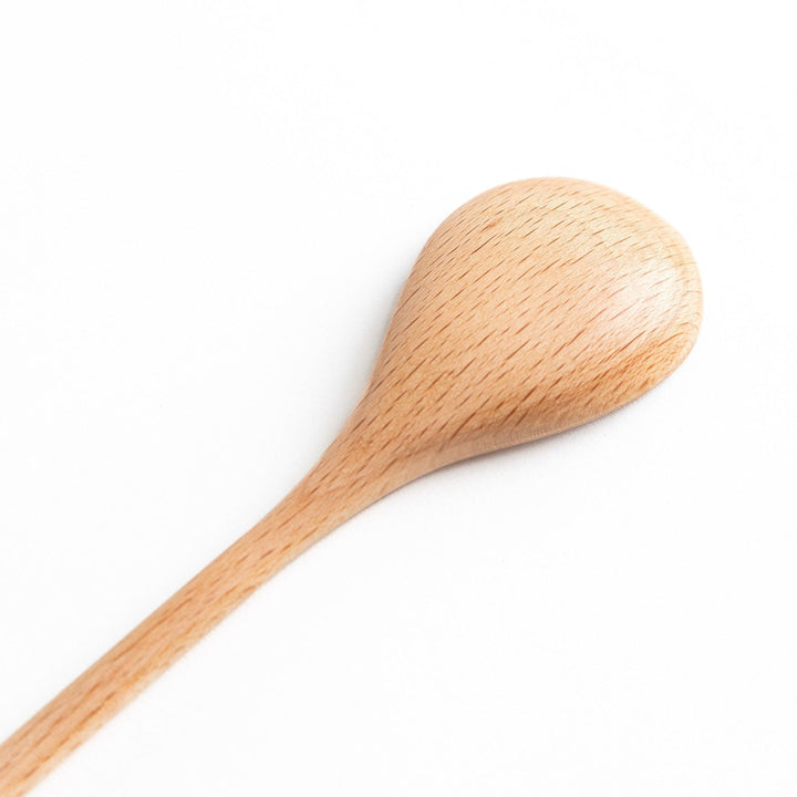 A set of four wooden soup spoons with wide, rounded bowls and colored tips—white, black, blue, and red.