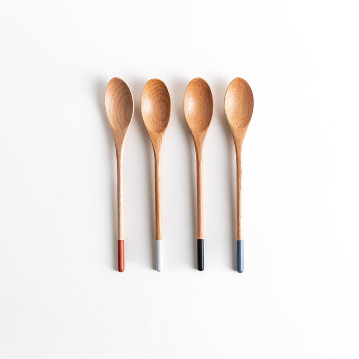 A set of four wooden curry spoons, each with a different colored tip—white, black, blue, and red.