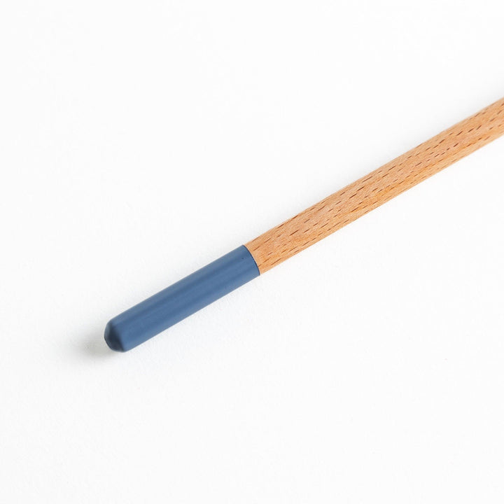 A set of four wooden curry spoons, each with a different colored tip—white, black, blue, and red.