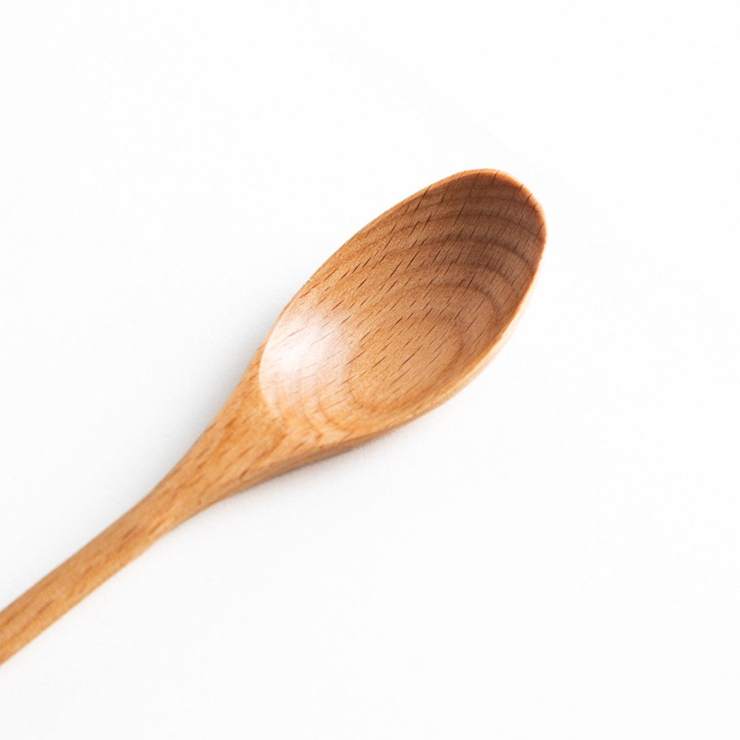 A set of four wooden curry spoons, each with a different colored tip—white, black, blue, and red.