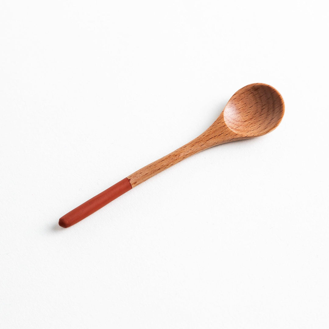 A set of four wooden tea spoons with wide, rounded bowls and colored tips—white, black, blue, and red.