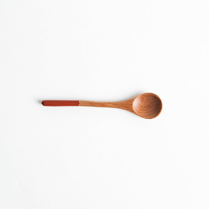 A set of four wooden tea spoons with wide, rounded bowls and colored tips—white, black, blue, and red.