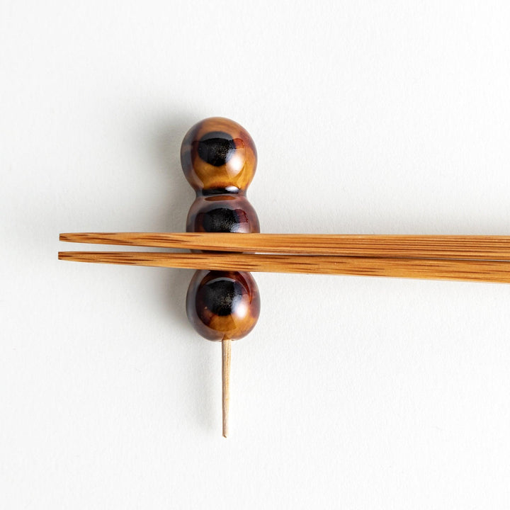 Ceramic chopstick rests shaped like Japanese dango skewers with with three brown balls.