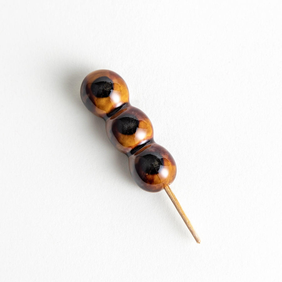 Ceramic chopstick rests shaped like Japanese dango skewers with with three brown balls.