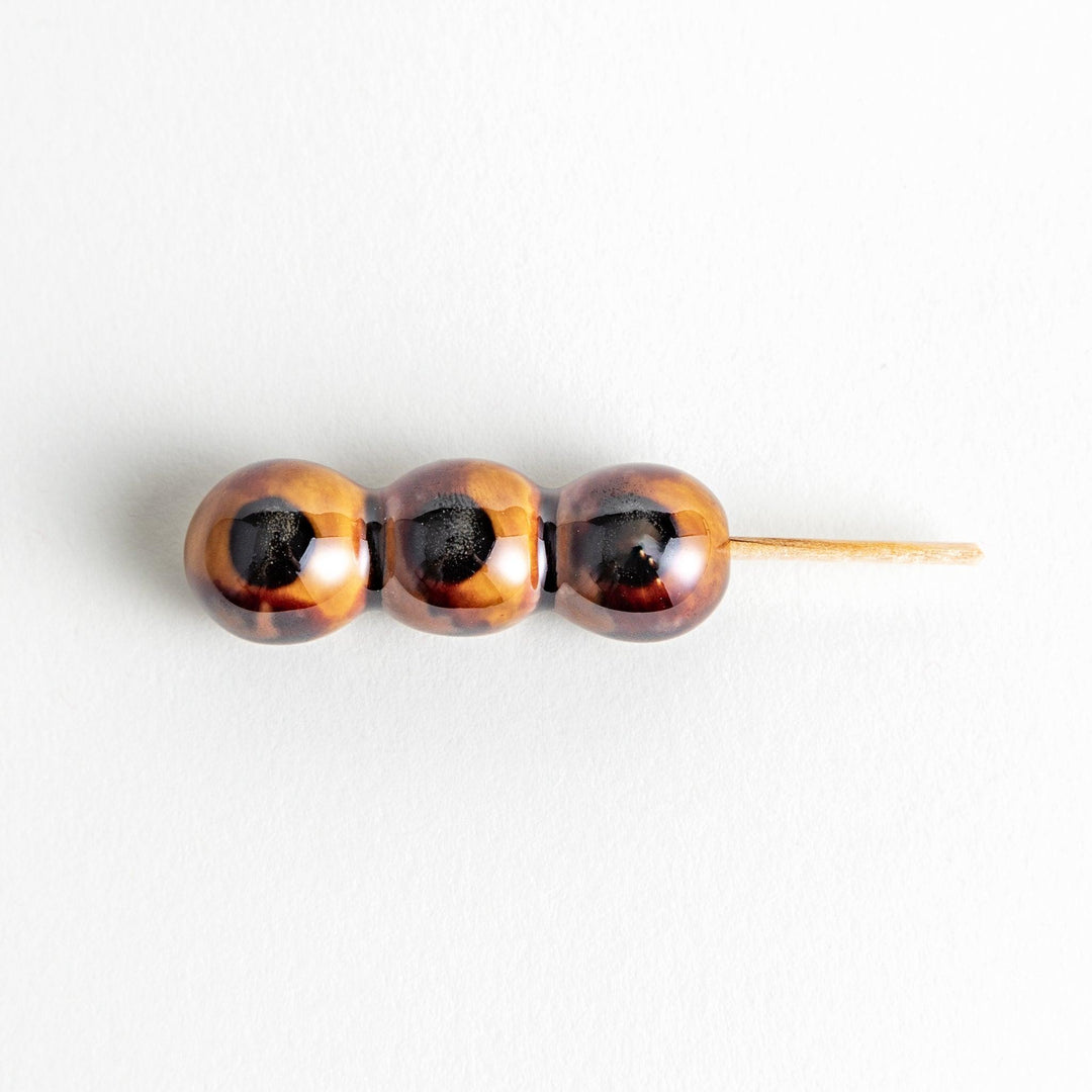 Ceramic chopstick rests shaped like Japanese dango skewers with with three brown balls.