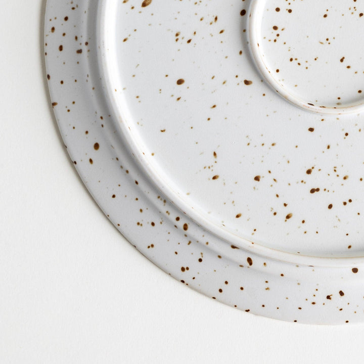 Round ceramic dinner plates, one in dark gray and the other in speckled white.