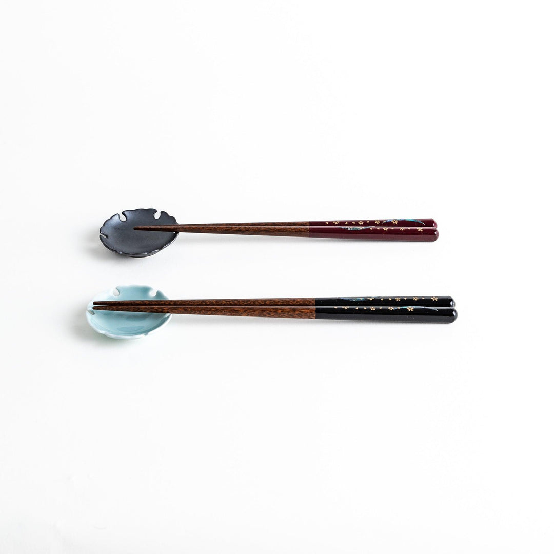 Two pairs of chopsticks, one with red and one with black handles, featuring moon and sakura design.