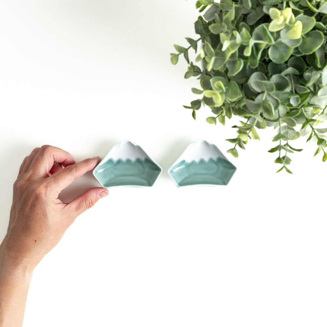 A small ceramic dish shaped like Mount Fuji with green and white colors.