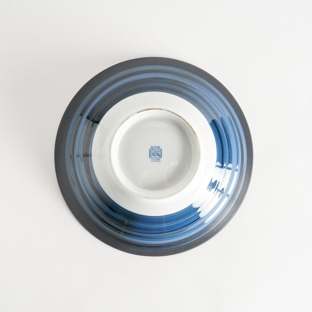 A bowl with a dark blue exterior and a white interior adorned with floral and wave patterns in blue and landscape in the cetner.