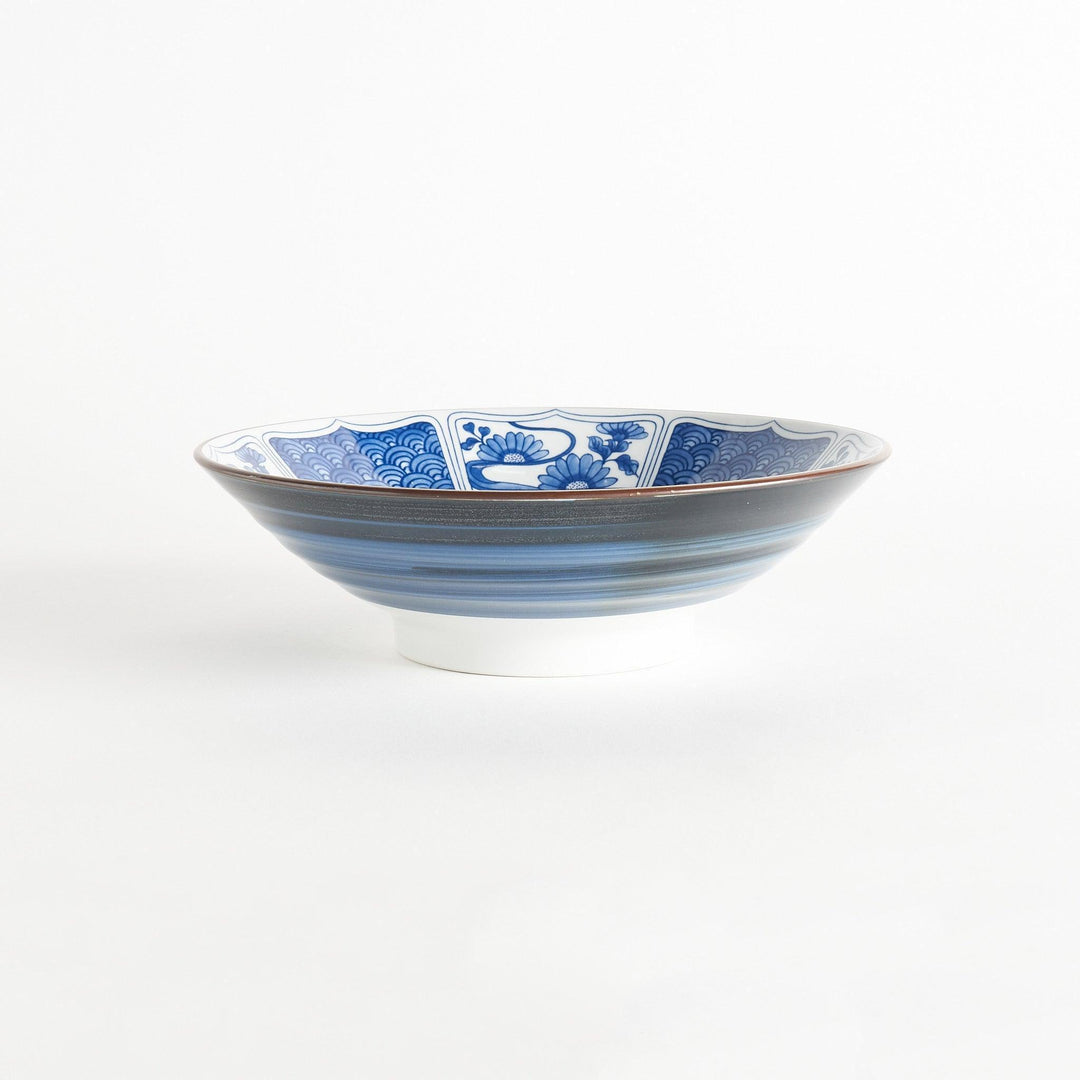 A bowl with a dark blue exterior and a white interior adorned with floral and wave patterns in blue and landscape in the cetner.