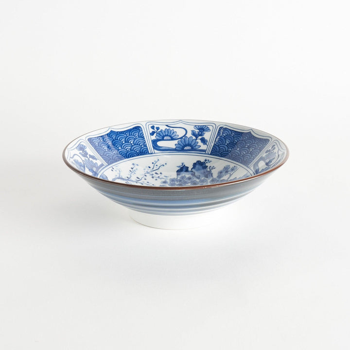 A bowl with a dark blue exterior and a white interior adorned with floral and wave patterns in blue and landscape in the cetner.