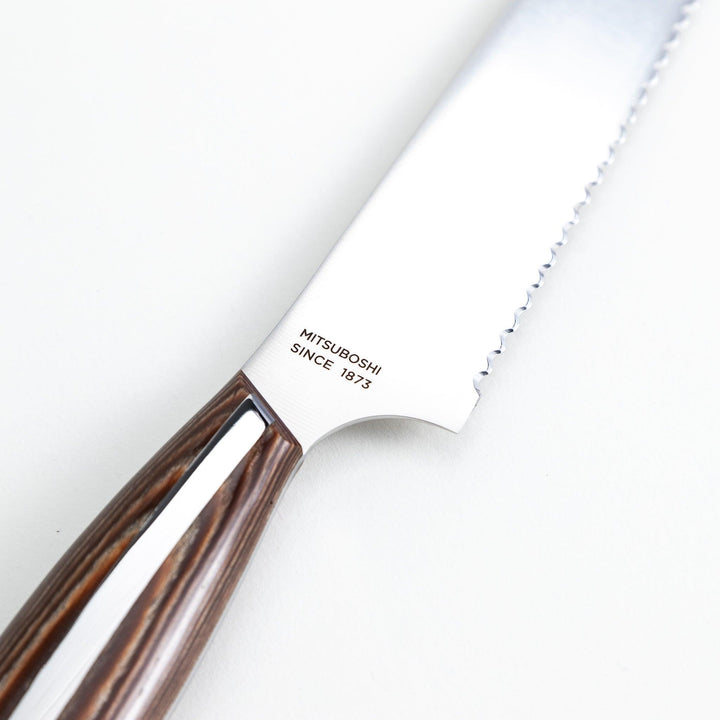 Nagomi bread knife with a serrated stainless steel blade and a polished wooden handle, displayed on a white background.