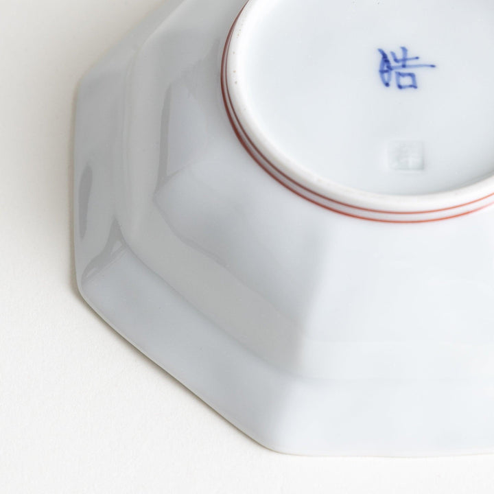 Small, white octagonal dessert bowls with thin blue and red lines forming geometric patterns.