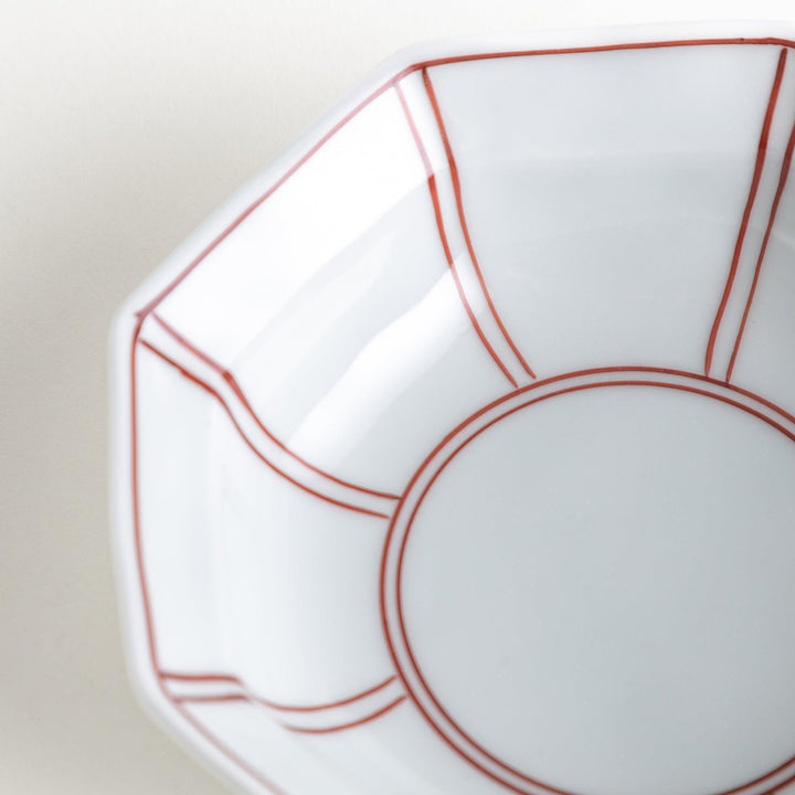 Small, white octagonal dessert bowls with thin blue and red lines forming geometric patterns.