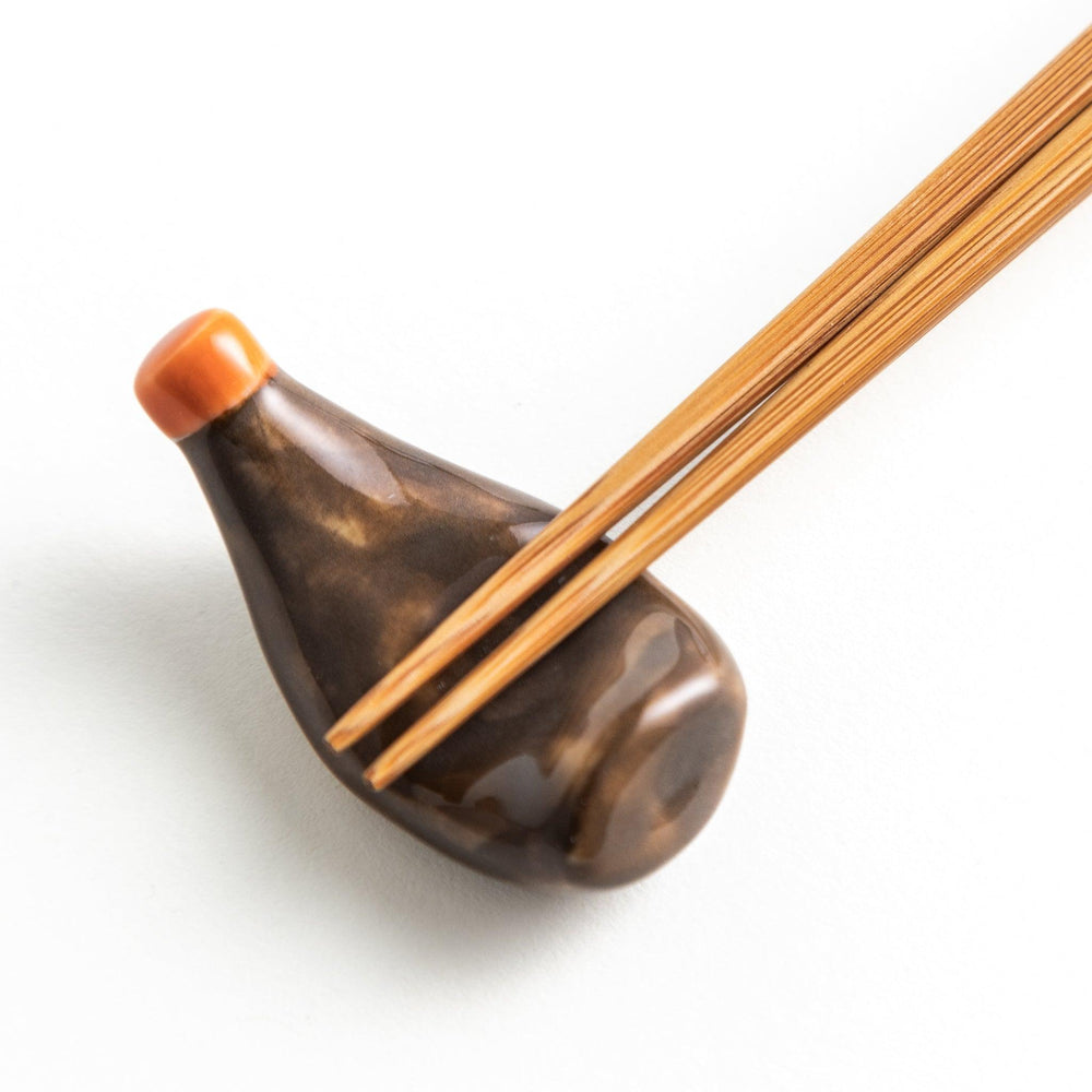 A ceramic chopstick rest resembling a okonomiyaki sauce bottle.