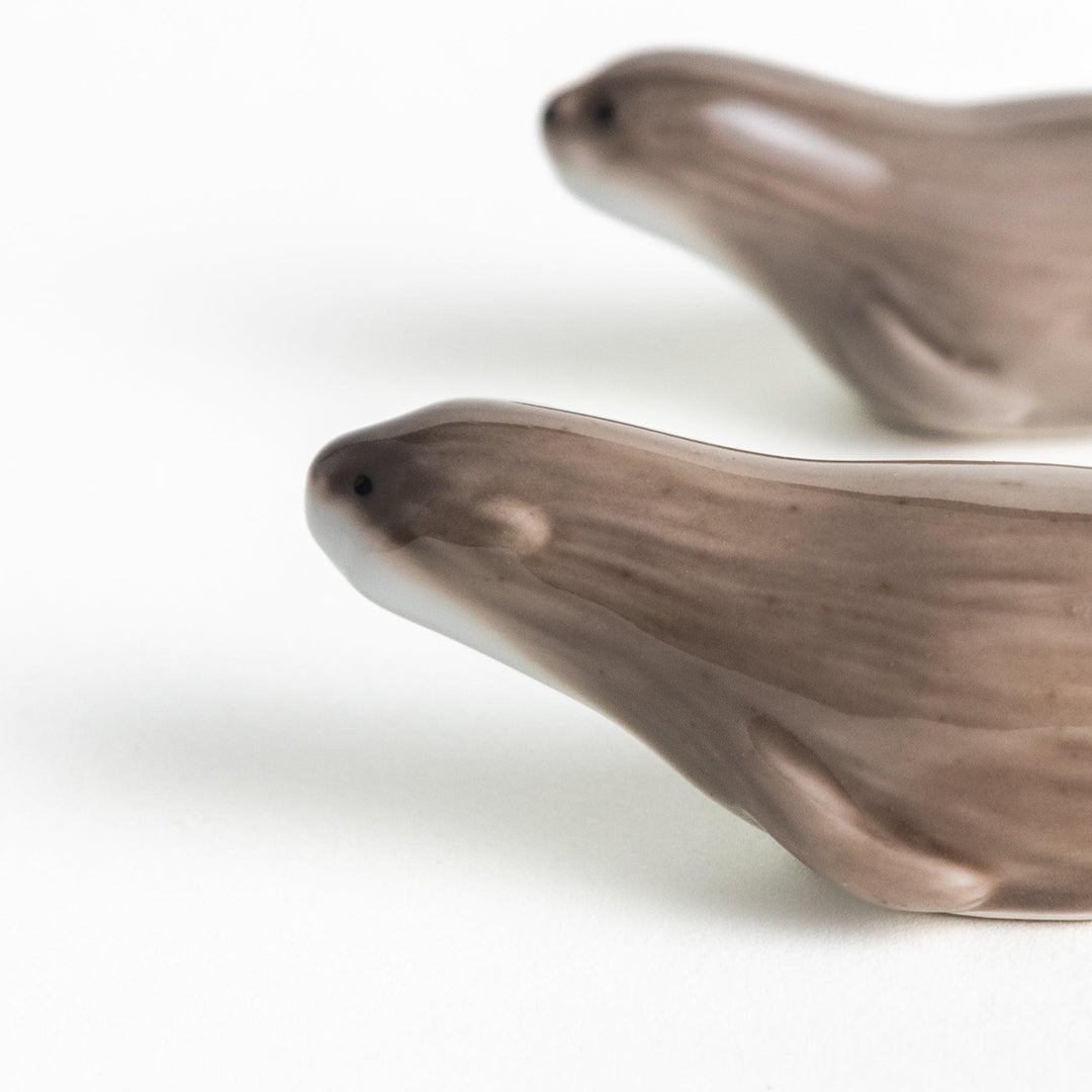 Two small, smooth, grey otters designed as chopstick rests.