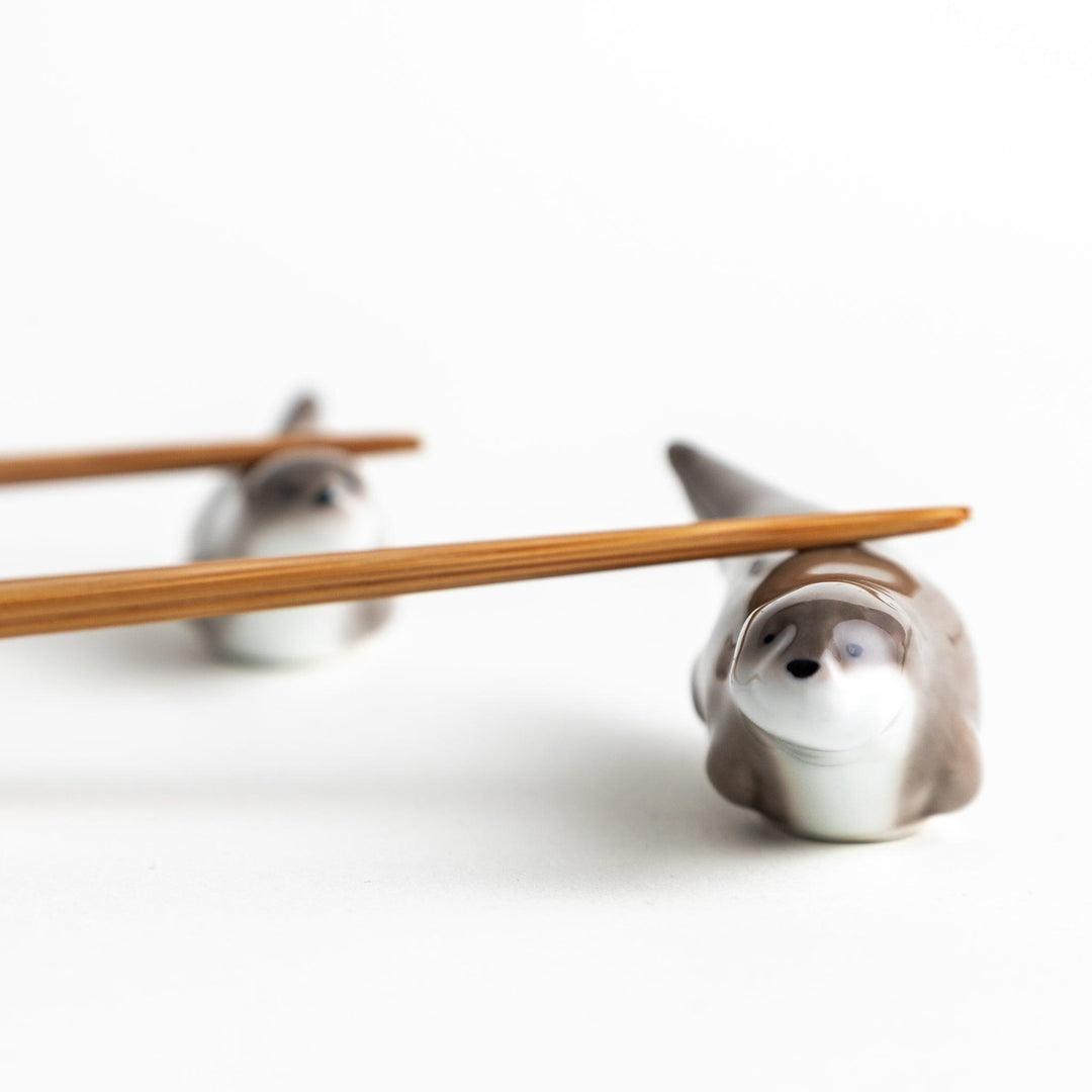 Two small, smooth, grey otters designed as chopstick rests.