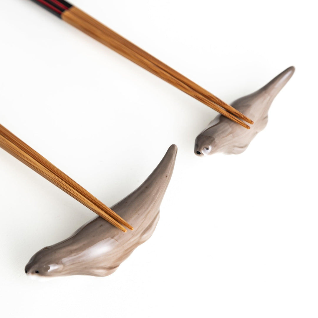 Two small, smooth, grey otters designed as chopstick rests.