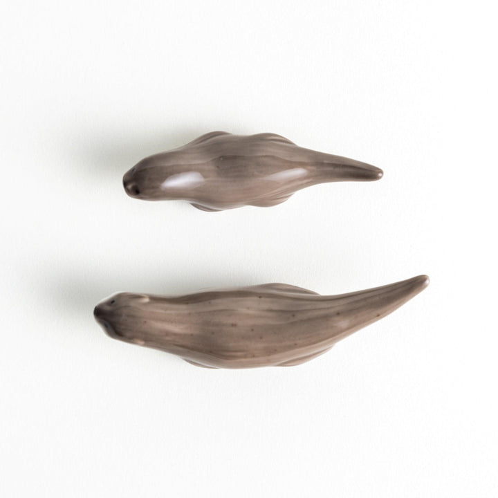 Two small, smooth, grey otters designed as chopstick rests.