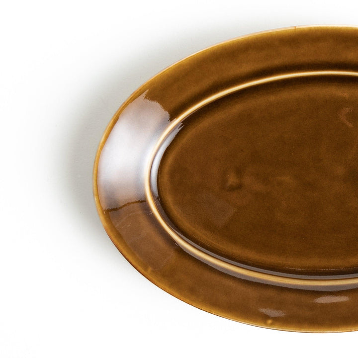 Sleek, dark brown or olive colored oval salad plate with a glossy finish, simple and minimalist.