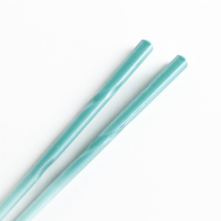 A set of chopsticks with twisted colored tops in soft pastel shades of pink, yellow, green, blue, and gray.