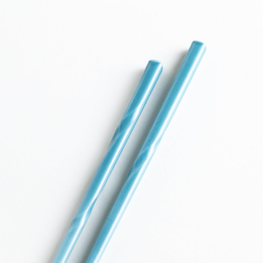 A set of chopsticks with twisted colored tops in soft pastel shades of pink, yellow, green, blue, and gray.