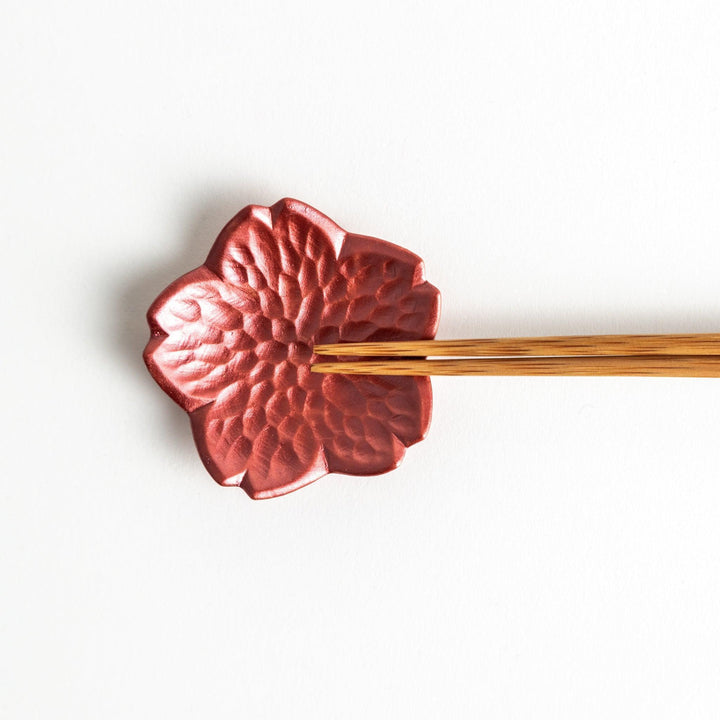 Small, flower-shaped chipsticks rest in different colors: yellow, blue, white, and pink, arranged in a square formation on a wooden surface.