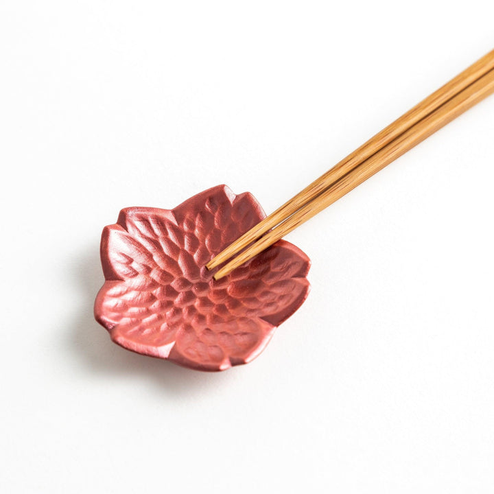 Small, flower-shaped chipsticks rest in different colors: yellow, blue, white, and pink, arranged in a square formation on a wooden surface.