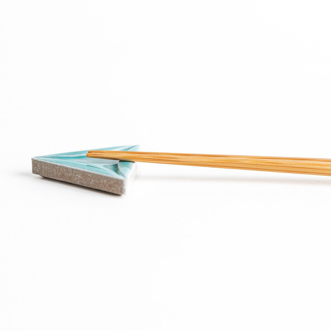 Five small, triangular ceramic chopstick rests in pastel colors—green, brown, blue, turquoise, and gray, arranged randomly on a white background.