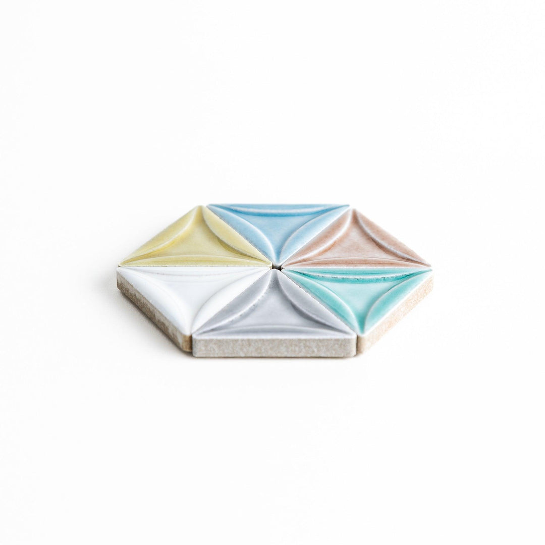 Five small, triangular ceramic chopstick rests in pastel colors—green, brown, blue, turquoise, and gray, arranged randomly on a white background.