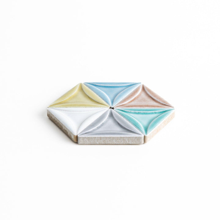 Five small, triangular ceramic chopstick rests in pastel colors—green, brown, blue, turquoise, and gray, arranged randomly on a white background.