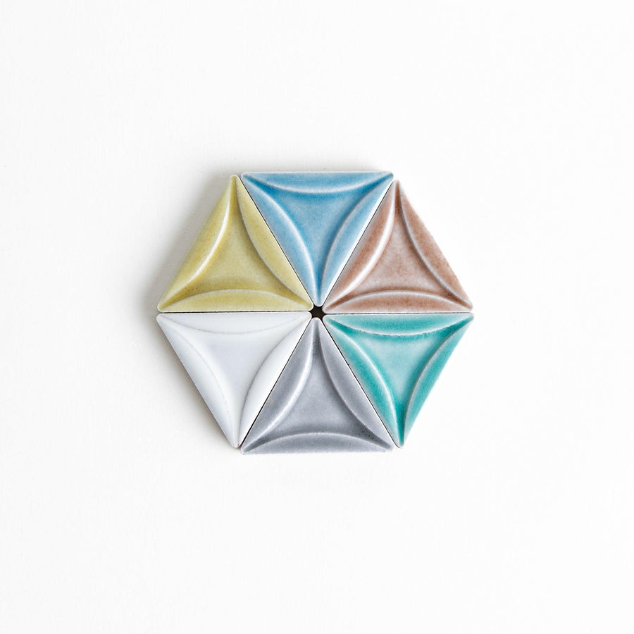 Five small, triangular ceramic chopstick rests in pastel colors—green, brown, blue, turquoise, and gray, arranged randomly on a white background.