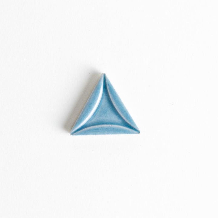 Five small, triangular ceramic chopstick rests in pastel colors—green, brown, blue, turquoise, and gray, arranged randomly on a white background.