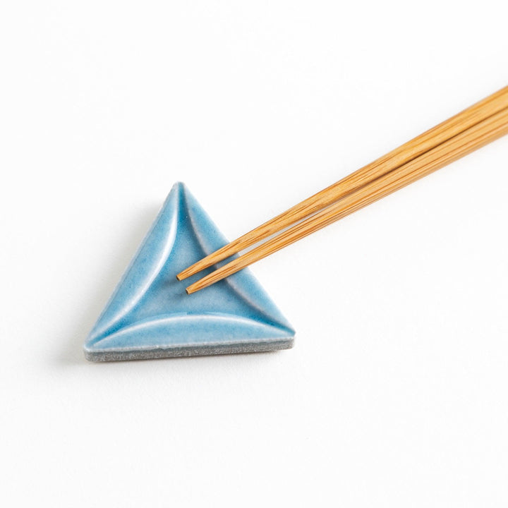 Five small, triangular ceramic chopstick rests in pastel colors—green, brown, blue, turquoise, and gray, arranged randomly on a white background.