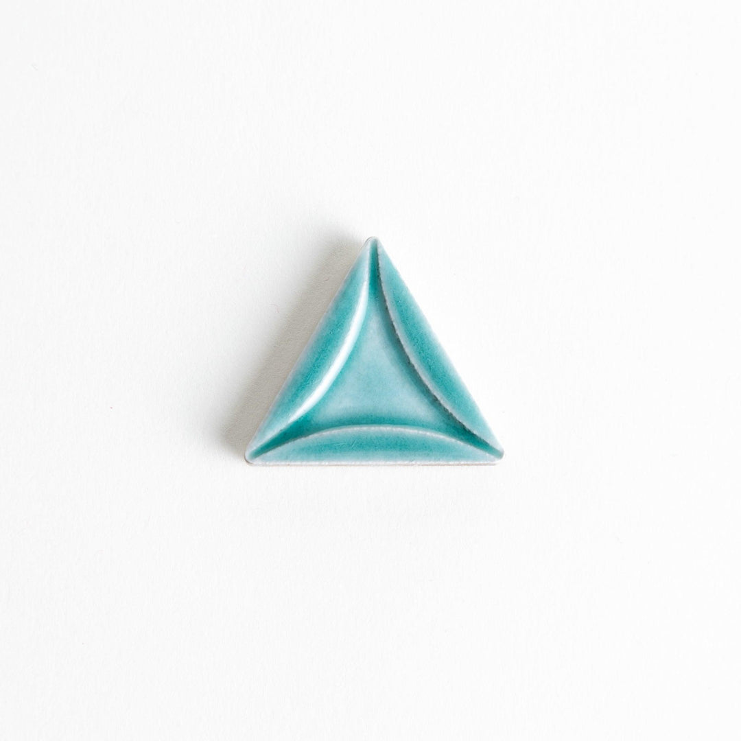 Five small, triangular ceramic chopstick rests in pastel colors—green, brown, blue, turquoise, and gray, arranged randomly on a white background.