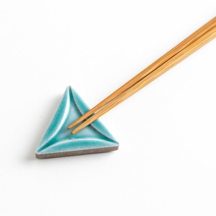 Five small, triangular ceramic chopstick rests in pastel colors—green, brown, blue, turquoise, and gray, arranged randomly on a white background.