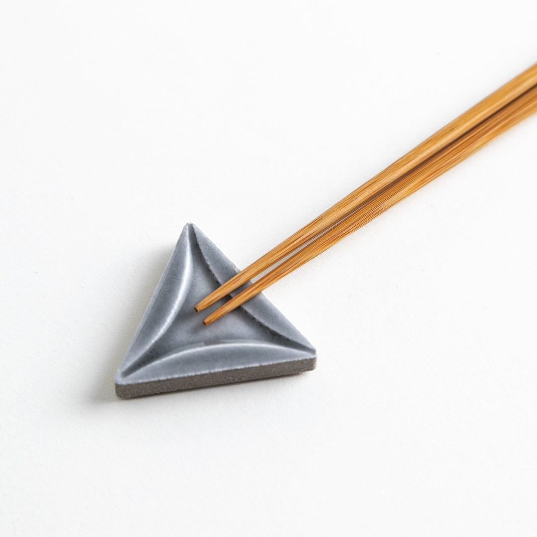 Five small, triangular ceramic chopstick rests in pastel colors—green, brown, blue, turquoise, and gray, arranged randomly on a white background.