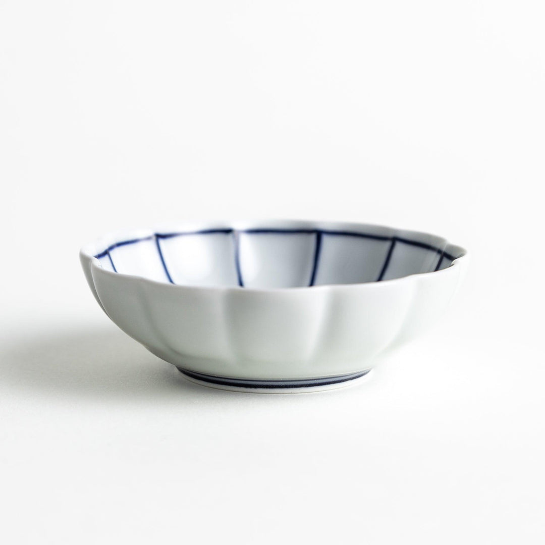 A small white porcelain condiment bowl with delicate blue or red lines radiating from the center, creating a simple yet elegant design.