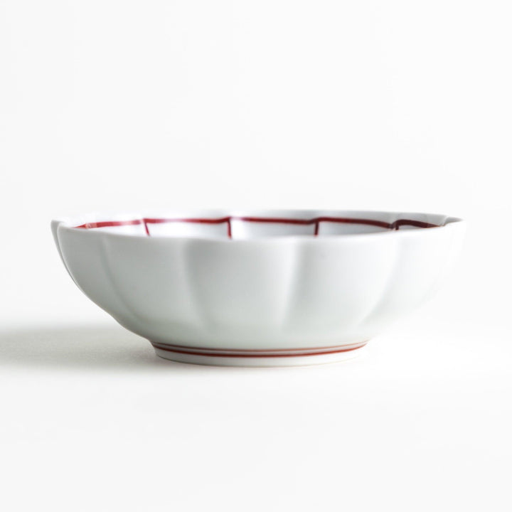 A small white porcelain condiment bowl with delicate blue or red lines radiating from the center, creating a simple yet elegant design.