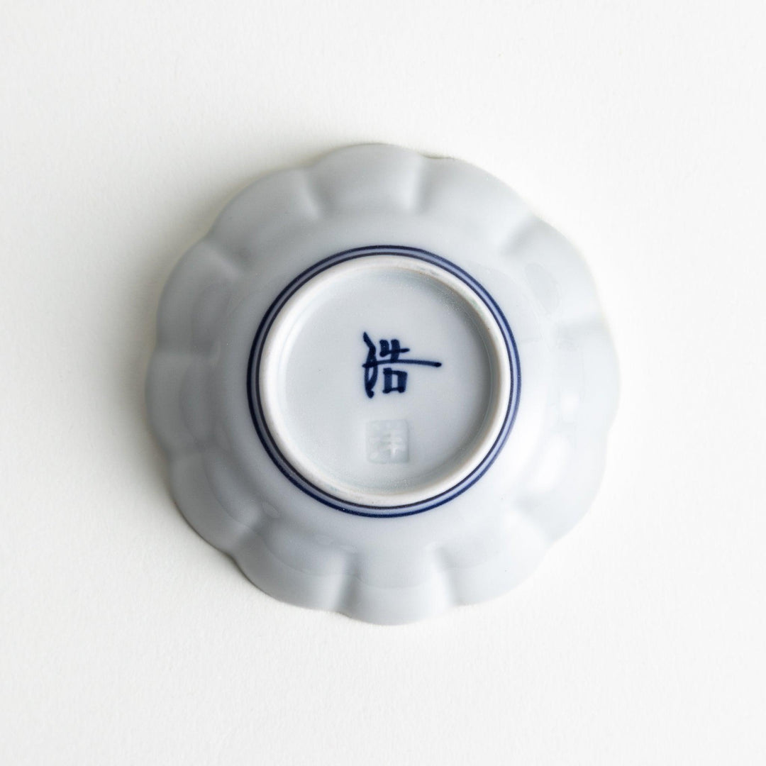 A small white porcelain condiment bowl with delicate blue or red lines radiating from the center, creating a simple yet elegant design.