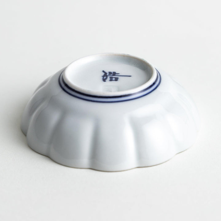 A small white porcelain condiment bowl with delicate blue or red lines radiating from the center, creating a simple yet elegant design.