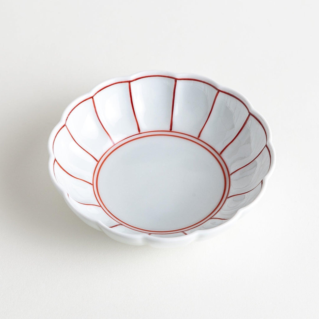 A small white porcelain dessert bowl with delicate blue or red lines radiating from the center, creating a simple yet elegant design.