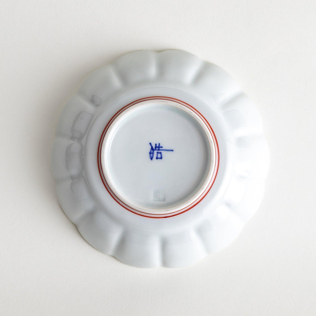 A small white porcelain dessert bowl with delicate blue or red lines radiating from the center, creating a simple yet elegant design.