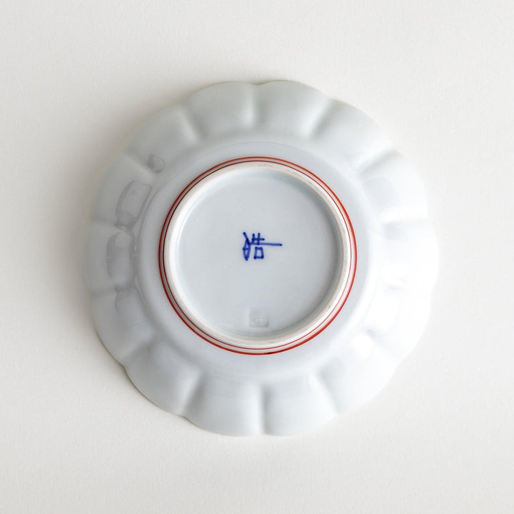 A small white porcelain dessert bowl with delicate blue or red lines radiating from the center, creating a simple yet elegant design.