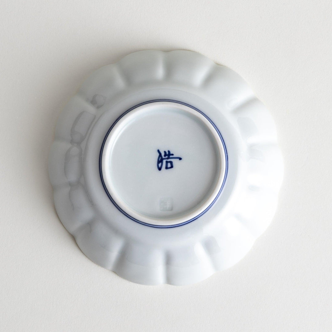 A small white porcelain dessert bowl with delicate blue or red lines radiating from the center, creating a simple yet elegant design.