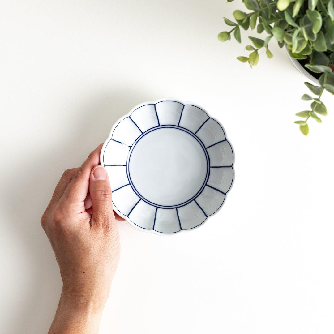 A small white porcelain dessert bowl with delicate blue or red lines radiating from the center, creating a simple yet elegant design.