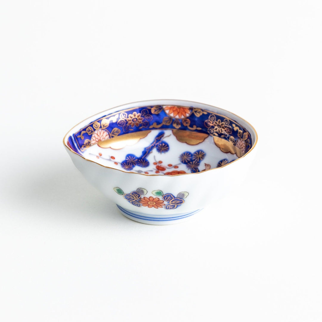 A small, triangular-shaped condiment bowl with intricate red, blue, and gold patterns featuring floral and geometric designs.