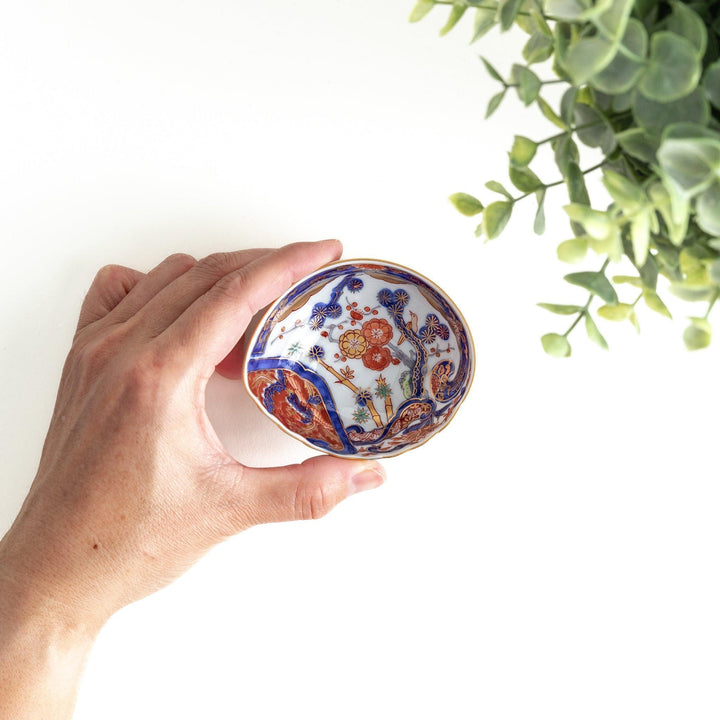 A small, triangular-shaped condiment bowl with intricate red, blue, and gold patterns featuring floral and geometric designs.