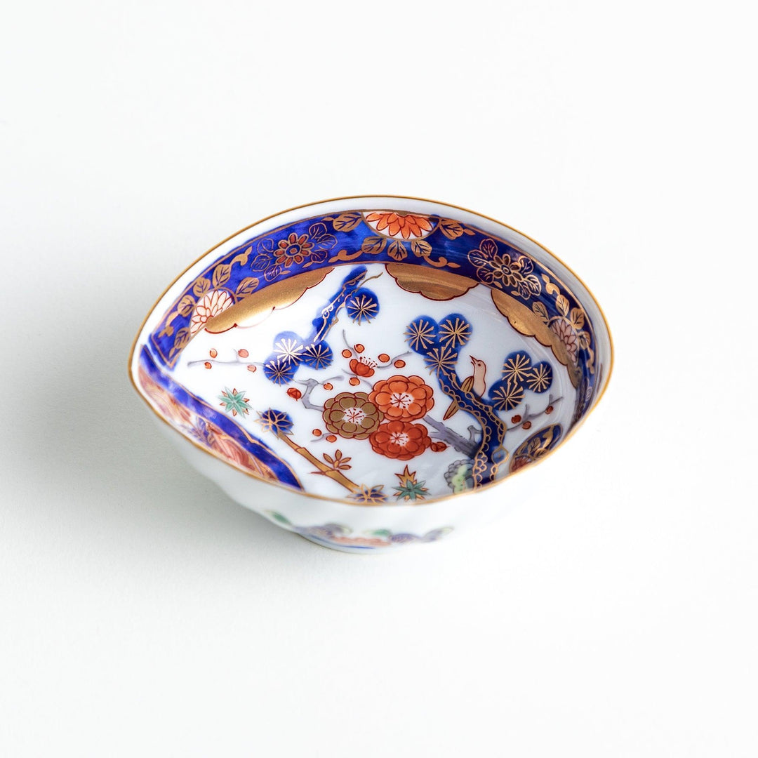 A small, triangular-shaped condiment bowl with intricate red, blue, and gold patterns featuring floral and geometric designs.