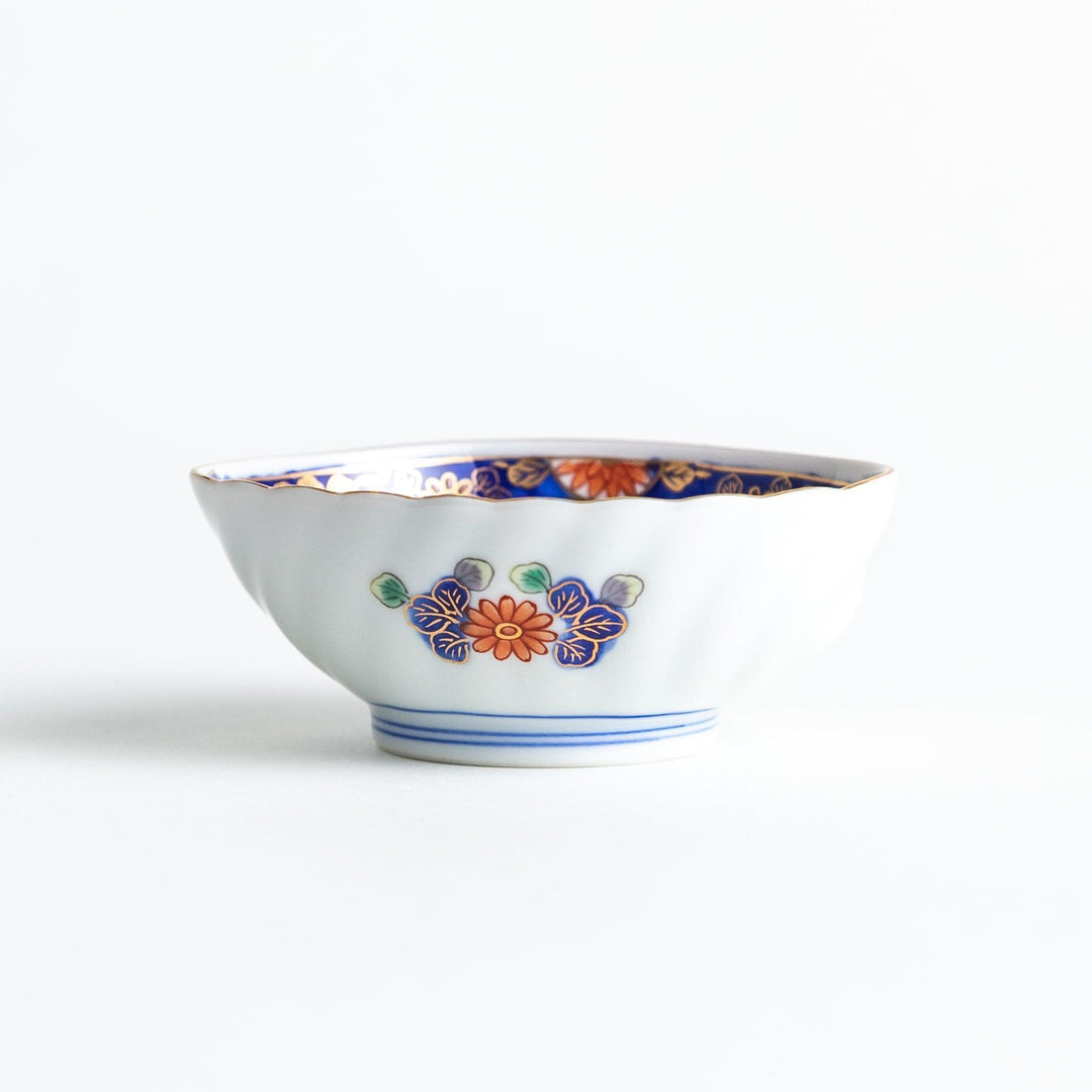 A small, triangular-shaped condiment bowl with intricate red, blue, and gold patterns featuring floral and geometric designs.